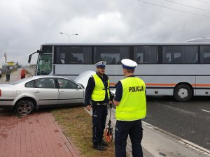 Zdjęcie pokazuje policjantów podczas czynności w sprawie wypadku z udziałem autobusu i pojazdu osobowego