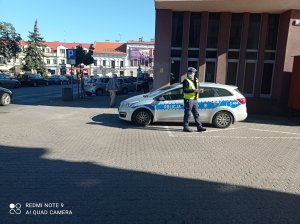 Policjant ruchu drogowego stoi przy radiowozie podczas akcji na Placu Wolności we Włocławku