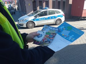 Policjant pokazujący materiały promujące bezpieczeństwo na drogach