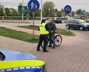 Policjantka rozmawia z rowerzystą i przekazuje opaskę odblaskową